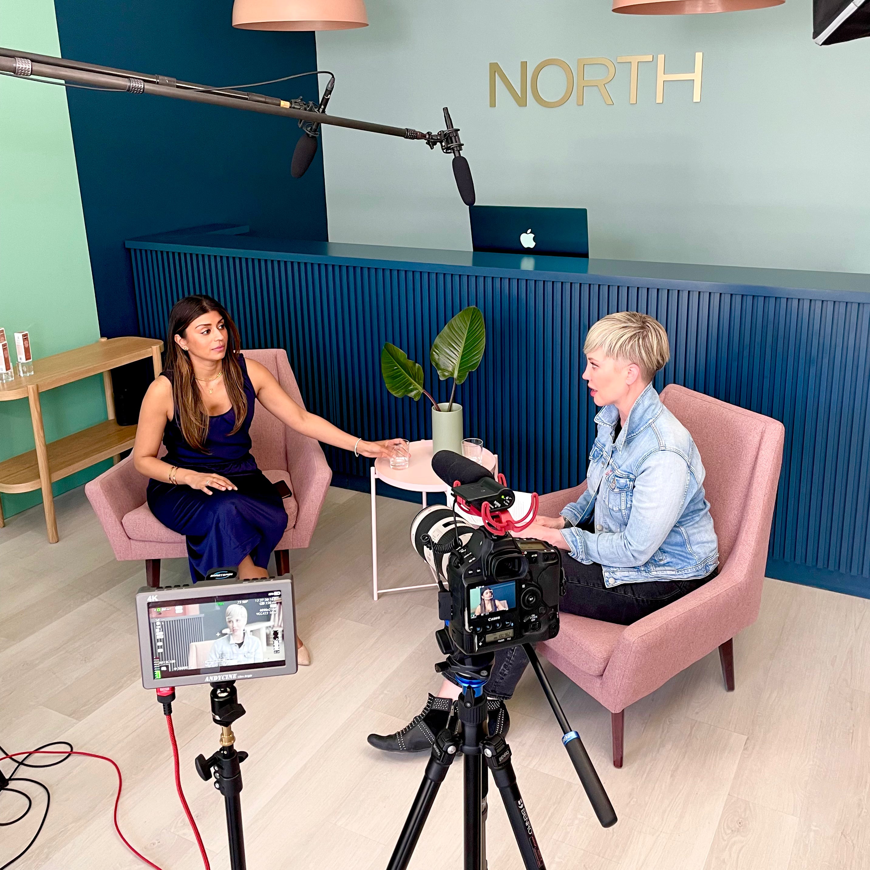 Two women in a professional setting with camera equipment and 'NORTH' branding.